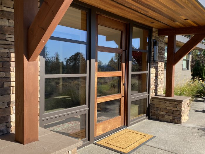 Updated front entryway. New overhang match to existing soffit and fascia detail. New stone column, post bracket and window detail flanking either side of entrance. Custom pivot style Mahogany door. Builder, remodel, entry remodel, carpentry, wood working, stone work, masonry, design, entrance rebuild